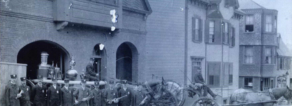 A group of firefighters stand in front of a fire house in Newport, Rhode Island. Picture is from the late 1800s.